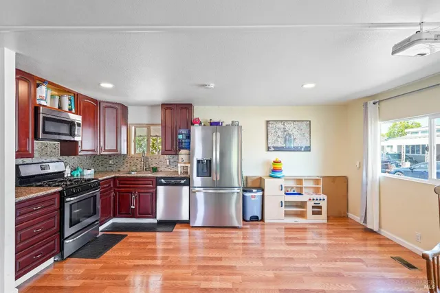 a kitchen with stainless steel appliances granite countertop a refrigerator stove top oven and sink