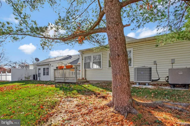 a view of a house with a large tree and sitting area