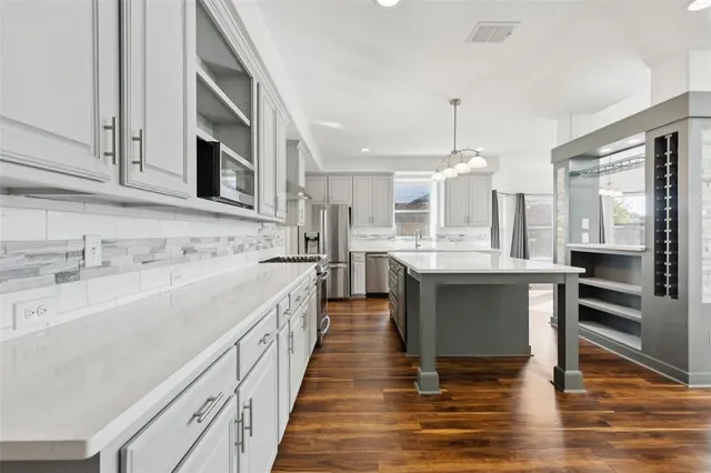 a large kitchen with stainless steel appliances kitchen island granite countertop a sink and cabinets