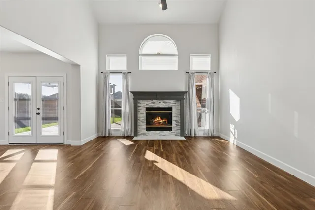 a view of an empty room with wooden floor fireplace and a window