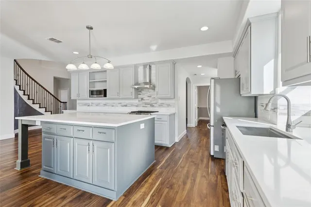 a kitchen with stainless steel appliances kitchen island granite countertop a sink stove and refrigerator