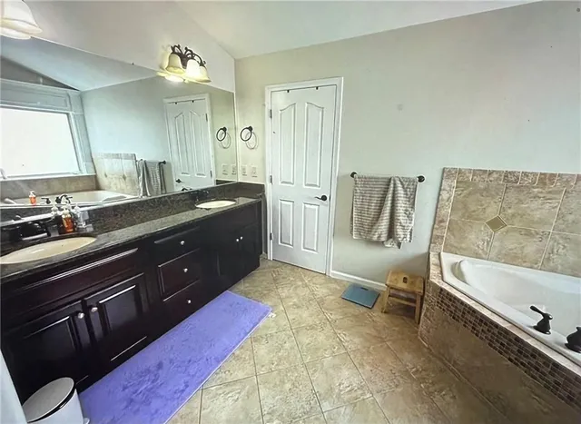 a spacious bathroom with a tub sink and mirror