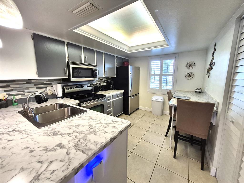 107 Windward Place, Unit 107 Oldsmar, FL 34677 - Photo 14 of 34 a kitchen with stainless steel appliances kitchen island granite countertop a sink dishwasher a microwave oven and a dining table with wooden floor