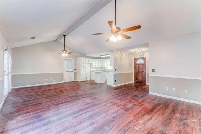 a front view of a house with a dirt yard and a large tree
