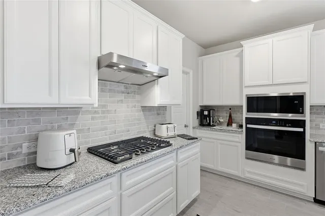 a kitchen with stainless steel appliances granite countertop a stove a white cabinets and a granite counter tops