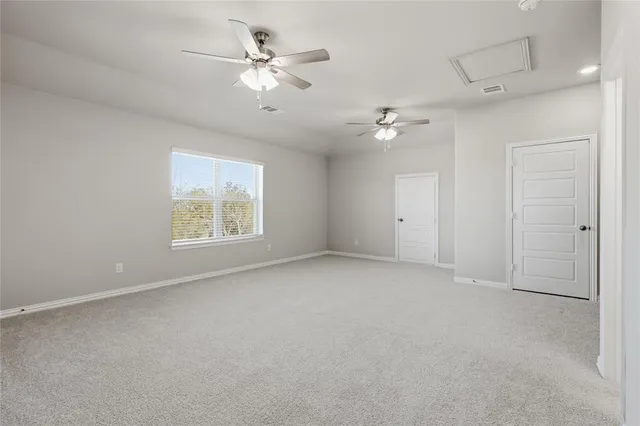 an empty room with chandelier fan and windows