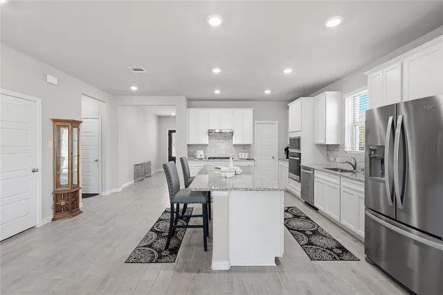 a kitchen with stainless steel appliances kitchen island granite countertop a refrigerator and a stove top oven