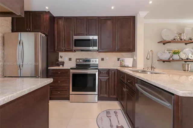 a kitchen with stainless steel appliances granite countertop a stove a sink and a refrigerator with wooden floor