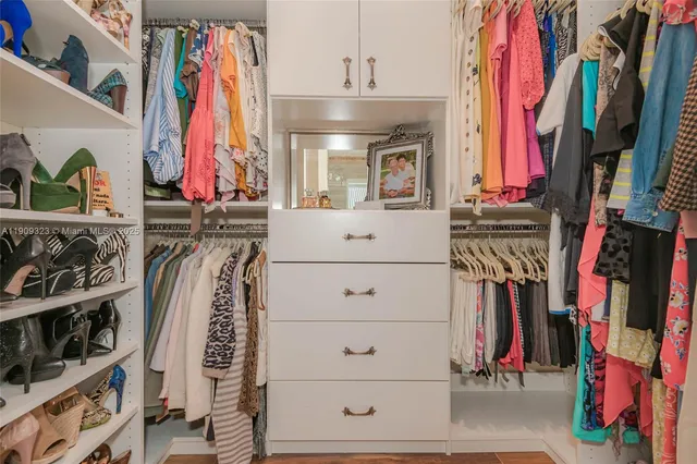 a view of walk in closet with clothes and shoes