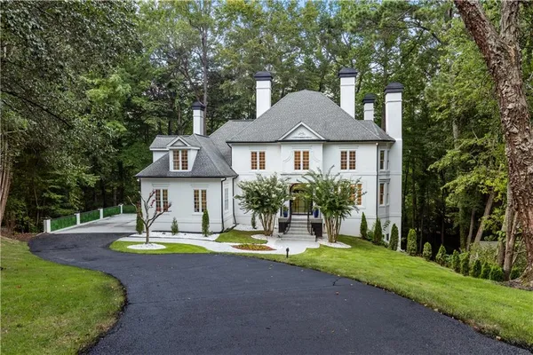 a front view of a house with a yard fountain and large tree