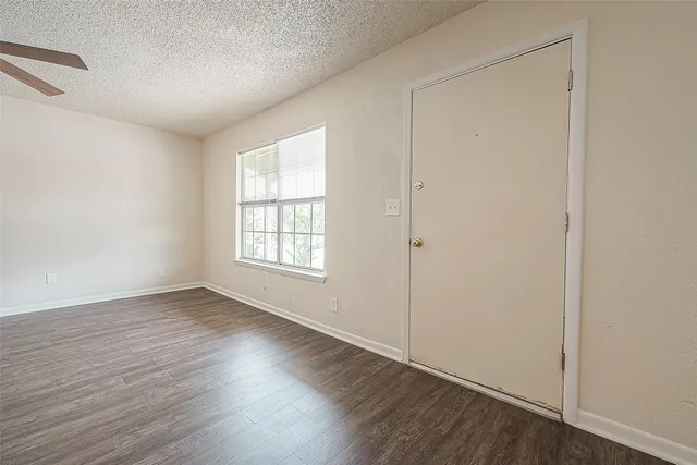 a view of empty room with wooden floor and ceiling fan