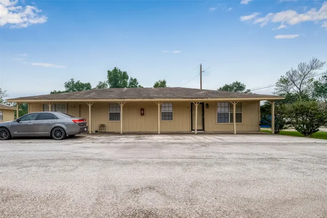 a view of a house with a barbeque and large trees
