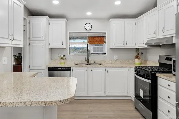 a kitchen with stainless steel appliances white cabinets a sink and a stove