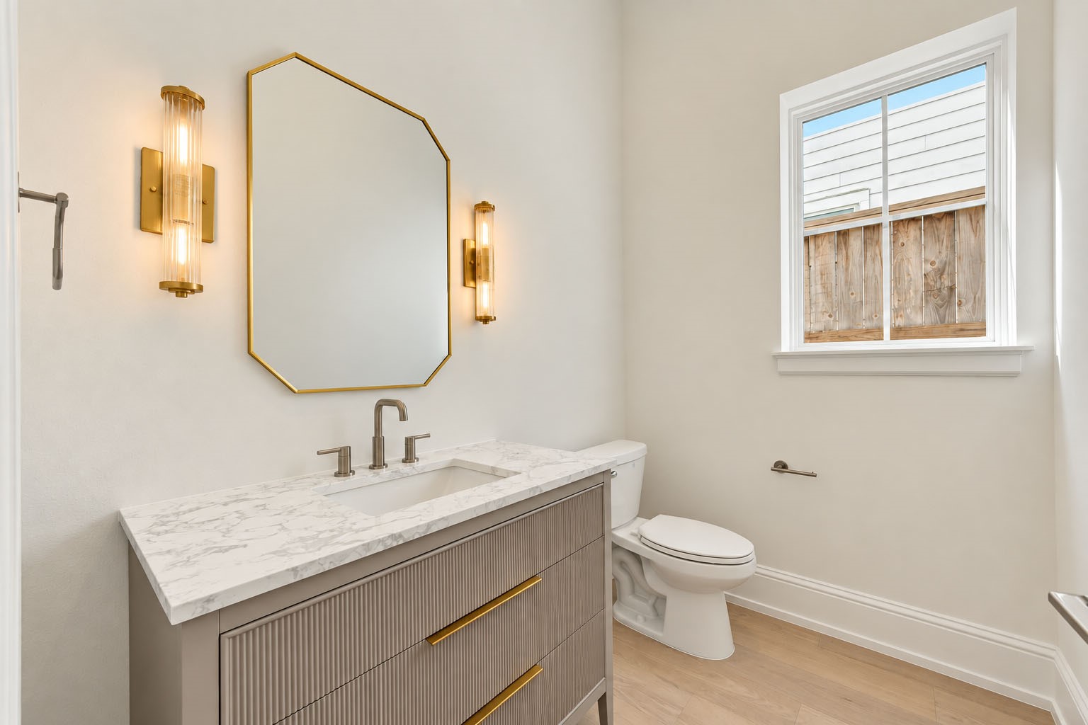2309 Hollister Road Houston, TX 77080 - Photo 17 of 47 Chic powder room makes a polished impression with a streamlined vanity, elegant stone countertop, brass-accented mirror, and designer wall sconces. Soft neutral finishes and natural light create a sophisticated, welcoming space thoughtfully designed for guests.