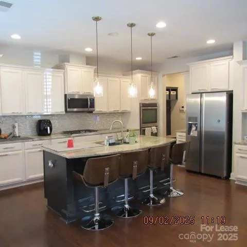 a kitchen with kitchen island granite countertop a sink a counter top space stainless steel appliances and cabinets