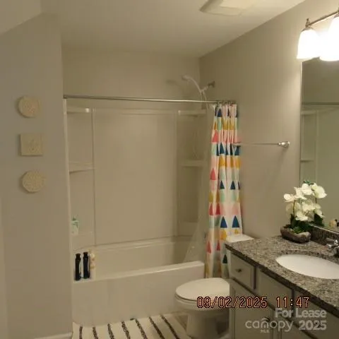 a bathroom with a granite countertop sink a toilet and shower