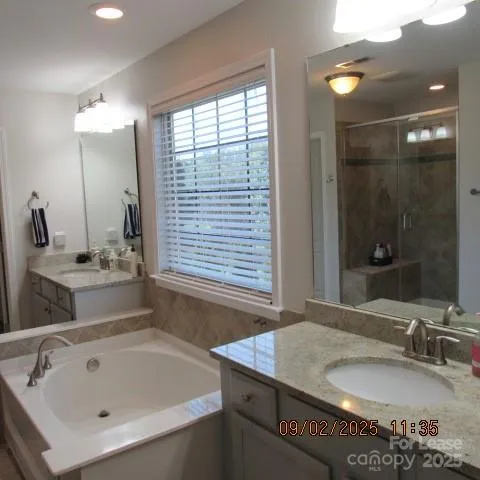 a bathroom with a granite countertop sink and a bathtub