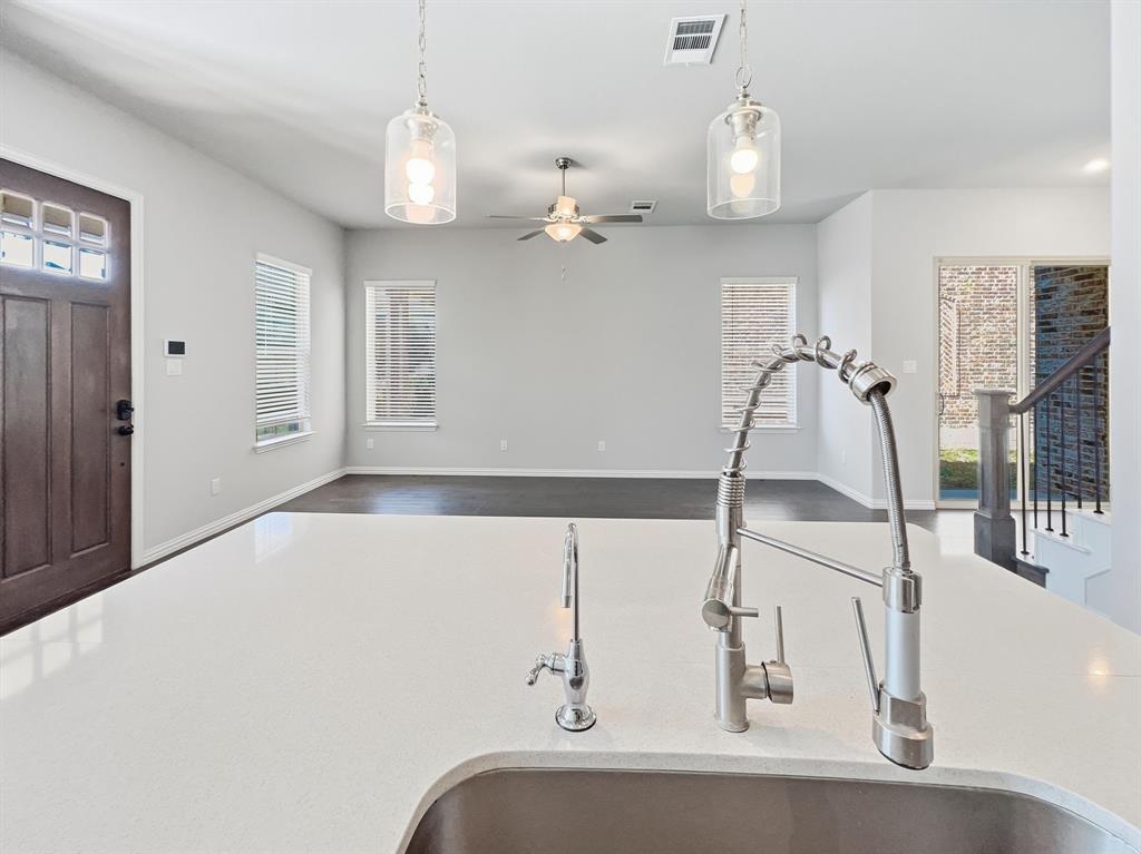 12632 Akenside Road Frisco, TX 75035 - Photo 9 of 40 Kitchen overlooking the main living area. The layout provides visibility across the open space and access to a sliding glass door on the right, leading to the backyard. The configuration supports functional flow between the kitchen, living area, and outdoor space.