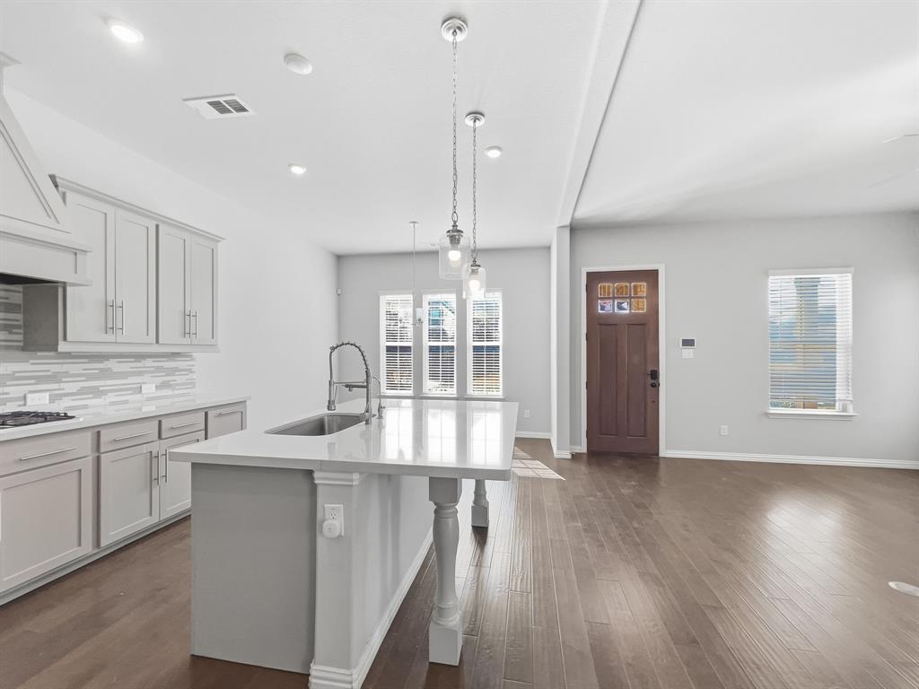 12632 Akenside Road Frisco, TX 75035 - Photo 10 of 40 a kitchen with kitchen island granite countertop a stove a sink a center island and wooden floor