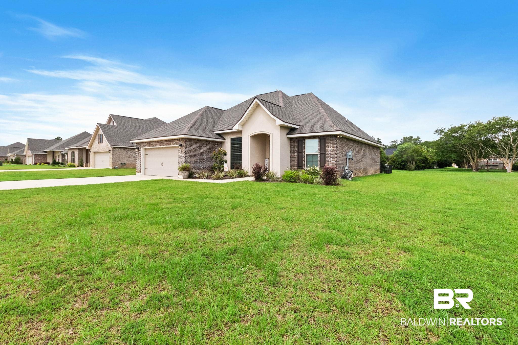 22244 Hibiscus Circle Foley, AL 36535 - Photo 3 of 51 Exterior residence with a prominent front facade, brick and stucco finishes, and a dark shingle roof
