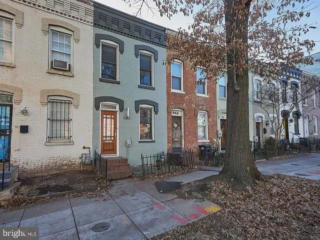 a view of a brick house with many windows next to a yard