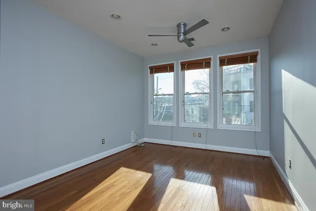 a view of an empty room with a window and wooden floor