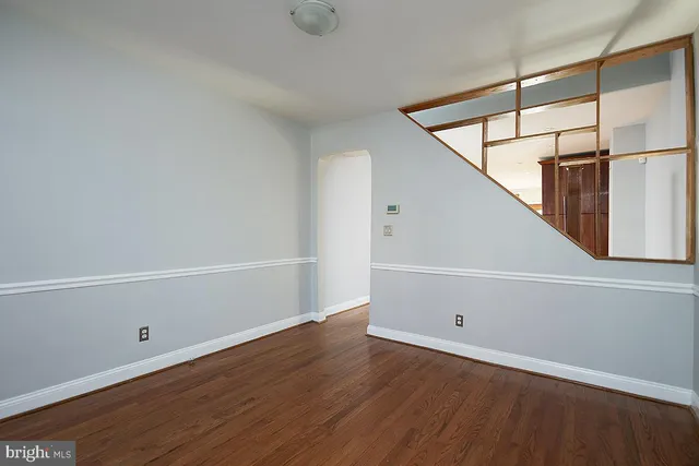 a view of an empty room with wooden floor and white walls