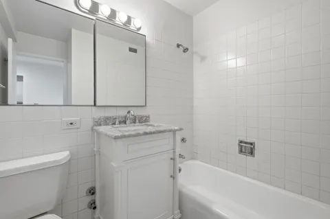 a bathroom with a granite countertop sink a toilet and shower
