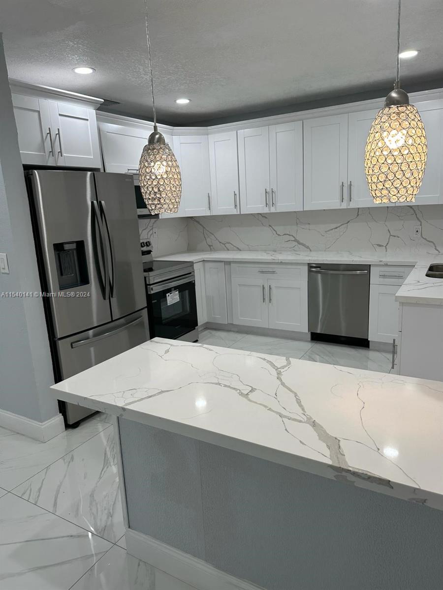 a kitchen with granite countertop a white cabinets and refrigerator
