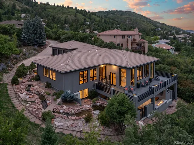 a view of a white house with a yard plants and large tree