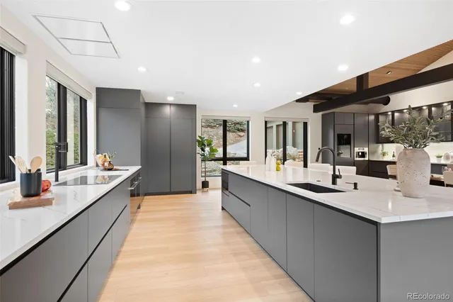 a large kitchen with a large counter top space a sink stainless steel appliances and cabinets