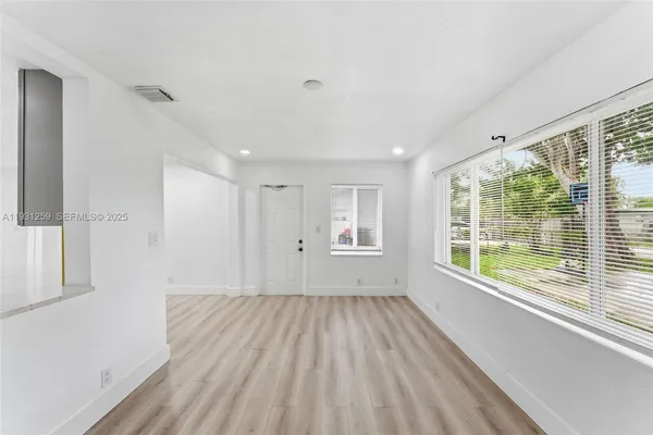 a view of an empty room with a window and wooden floor