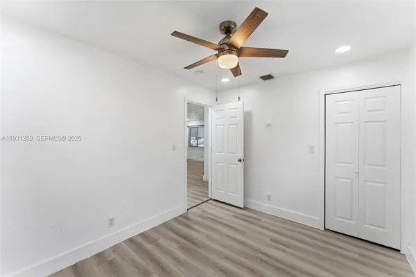 an empty room with wooden floor and ceiling fan