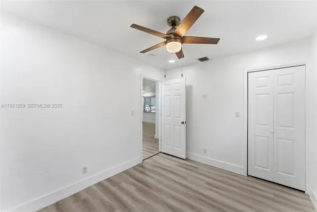 an empty room with wooden floor and ceiling fan