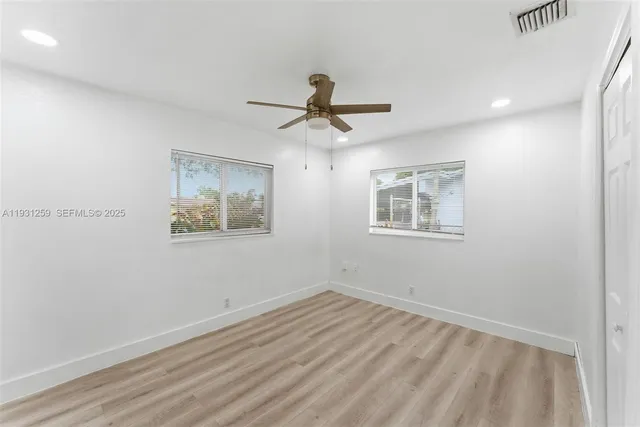 a view of empty room with wooden floor and ceiling fan