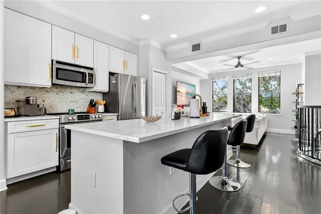 a kitchen with stainless steel appliances a sink a stove a refrigerator cabinets and a dining table with wooden floor