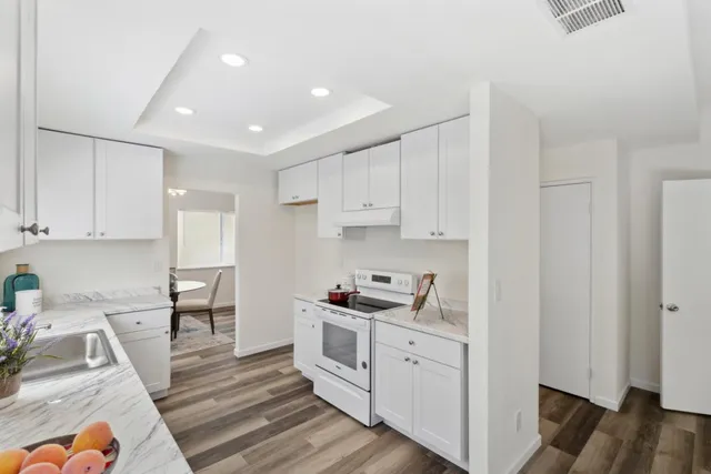 a kitchen with white cabinets and sink