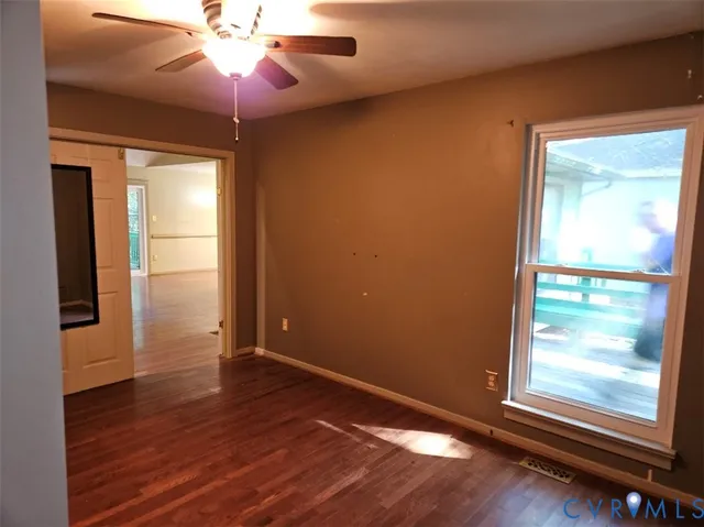 a view of empty room with wooden floor and fan