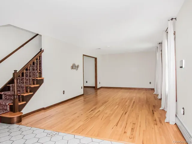 a view of an empty room with wooden floor and stairs