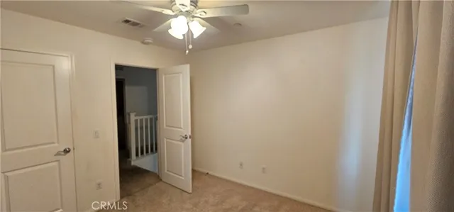 an empty room with a bathroom and a chandelier fan