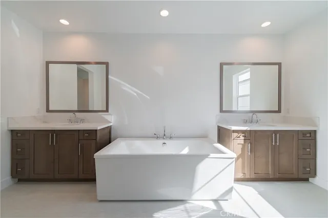 a spacious bathroom with a tub double sink and mirror