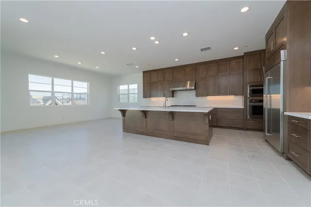 a large kitchen with a large counter top stainless steel appliances and cabinets
