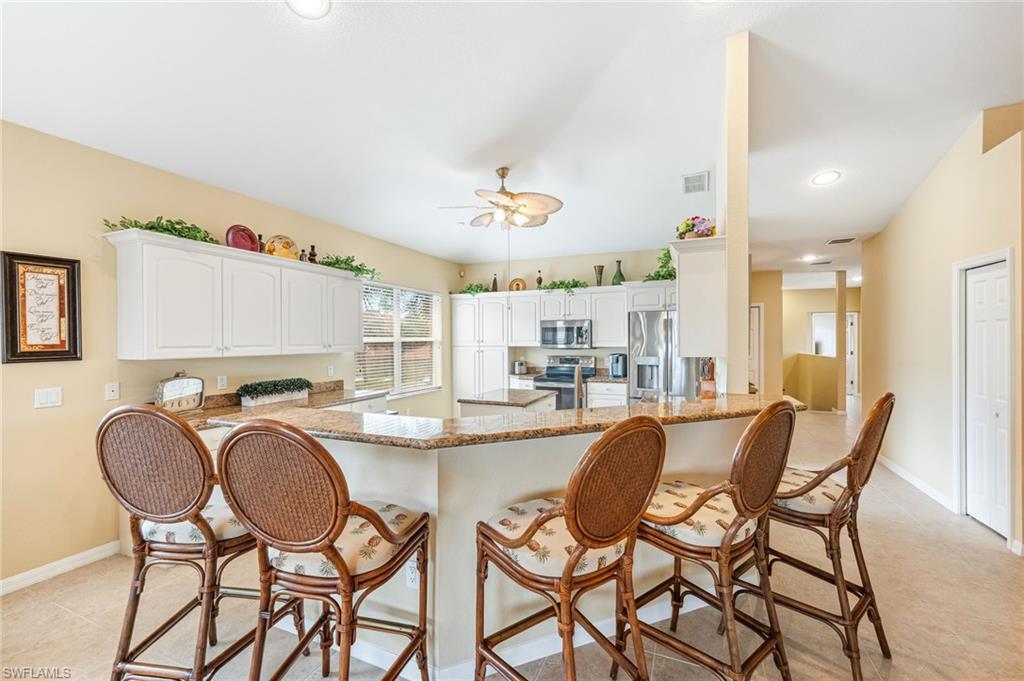 20051 Seagrove Street, Unit 1208 Estero, FL 33928 - Photo 5 of 25 a dining hall with stainless steel appliances a dining table and chairs with kitchen island