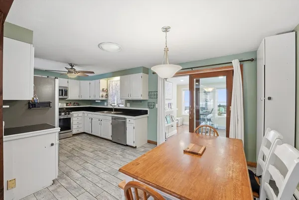 a kitchen with stainless steel appliances kitchen island granite countertop a sink a stove and white cabinets