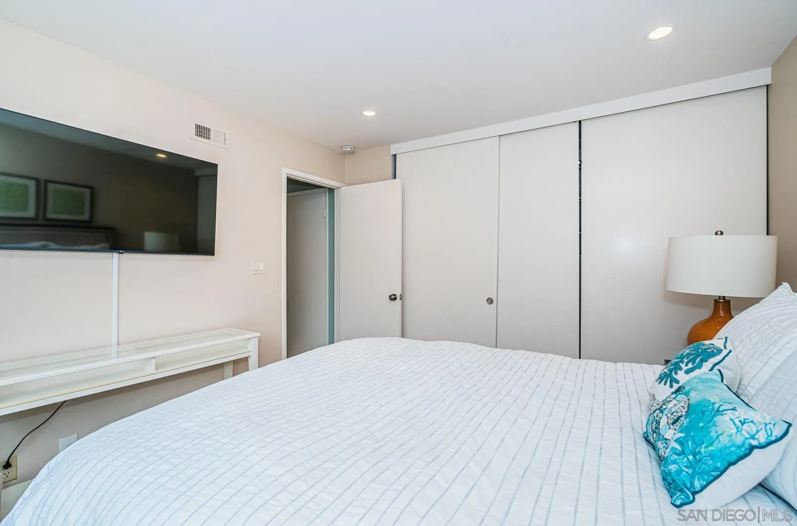 901 Caminito Madrigal, Unit E Carlsbad, CA 92011 - Photo 19 of 28 a bedroom with a bed and a flat screen tv
