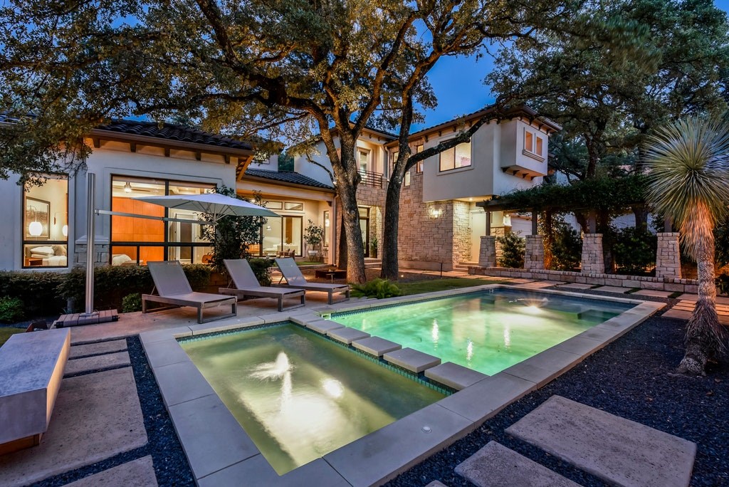 a view of swimming pool with outdoor seating and house in the background