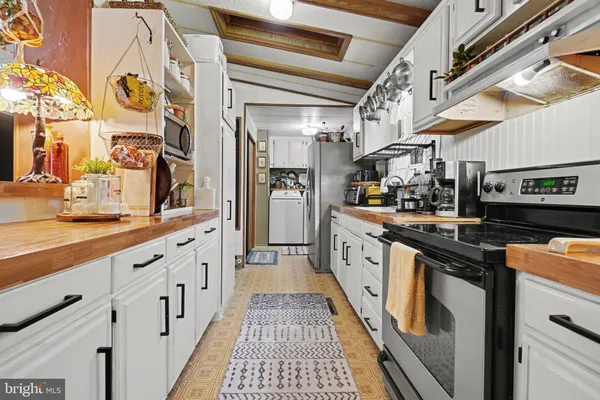 a large white kitchen with stainless steel appliances granite countertop lots of counter space and wooden floor
