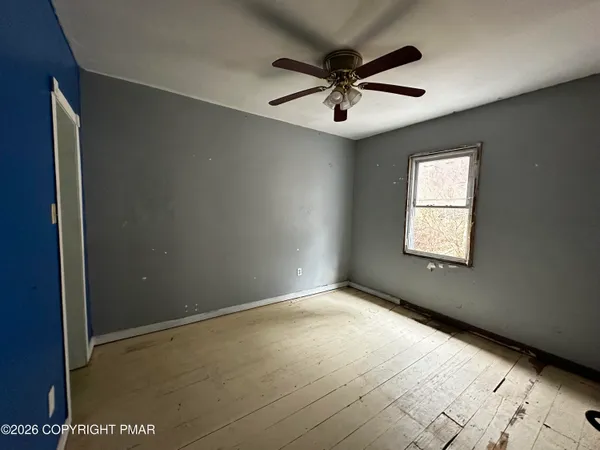 an empty room with windows and fan