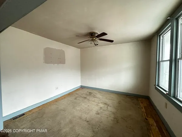 an empty room with windows and fan