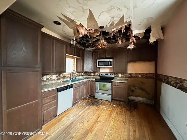 a kitchen with kitchen island granite countertop a sink cabinets and stainless steel appliances